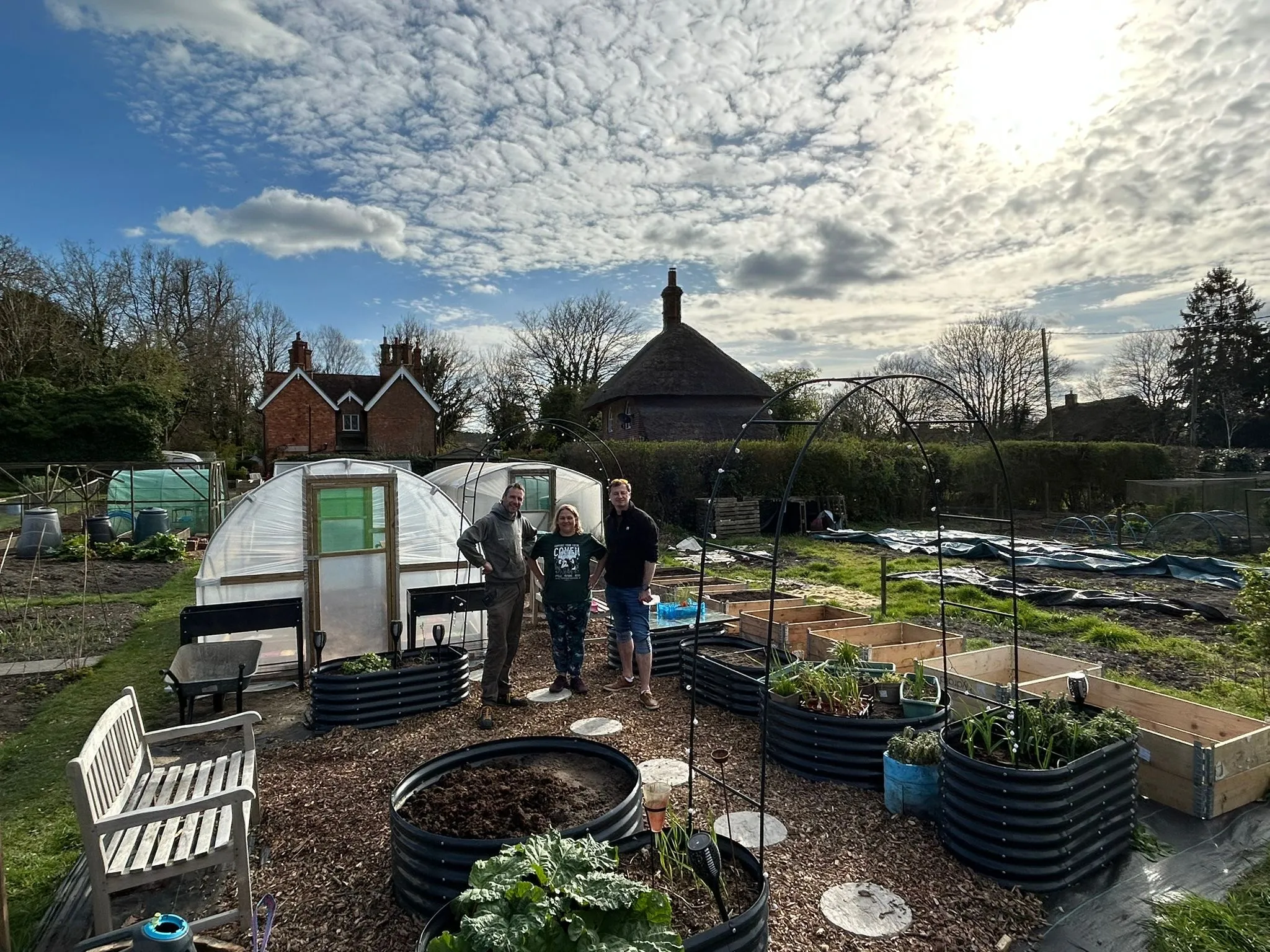 Volunteers standing among the raised beds and polytunnel at the HEG Grows plot
